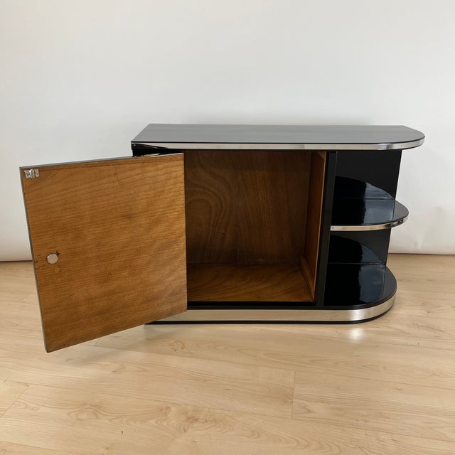 Small asymmetrical Art Deco Lowboard from France around 1930. Black, high-gloss polished piano lacquer on wood. Door with...