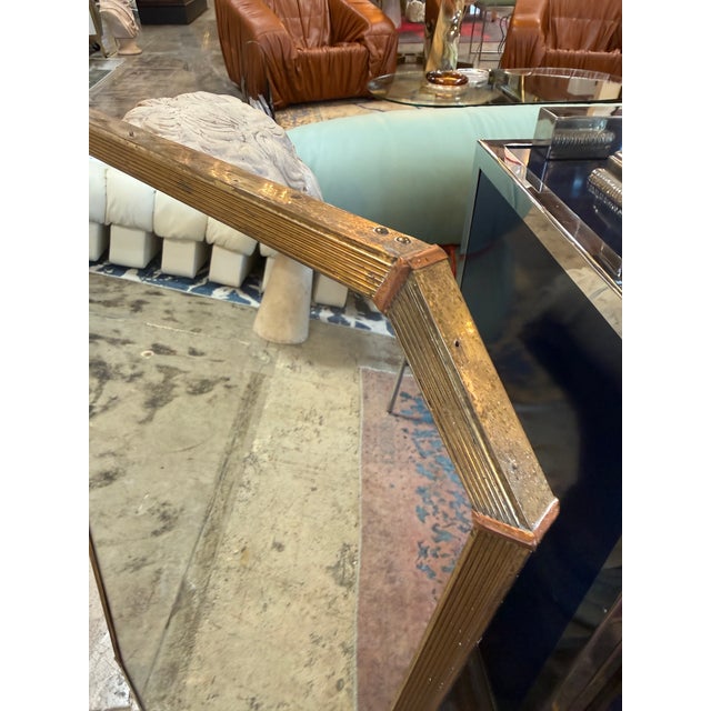 Elegant Italian wall mirror featuring an elongated, gently tapered shape with clipped corners and a slender ribbed brass...