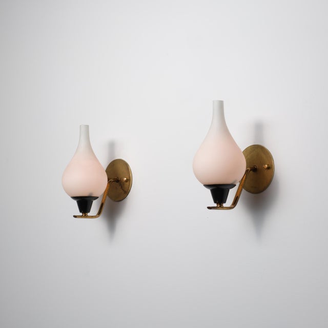 Pair of Italian Mid-Century Modern wall sconces made of brass with black lacquered metal elements and solid opaline glass...