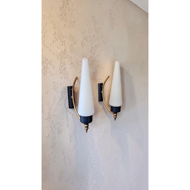 Pair of opaline glass and brass wall lamps made in the 1950s in the style of Milan's Stilnovo. The inverted cone-shaped...
