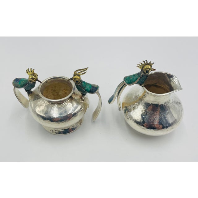 A whimsical and collectible 1950s silver-plated creamer and sugar caddie set designed and manufactured by the legendary...