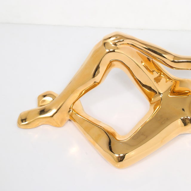 This Mid-Century gold-plated ceramic sculpture, depicting a reclining woman, is a captivating work of American design...