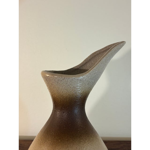 A beautifully sculptural mid-century modern studio pottery pitcher featuring an elegant asymmetrical spout and an organic...