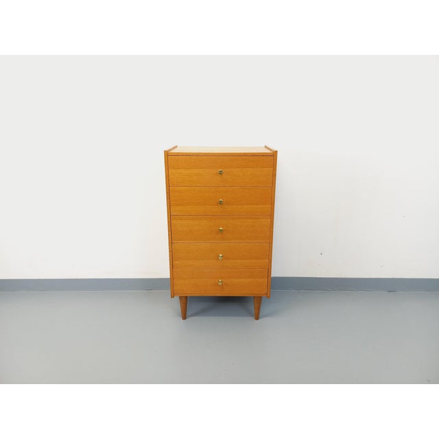 Vintage 1950s/60s oak chest of drawers, featuring five large drawers with elegant, small, gold-tone brass handles and...