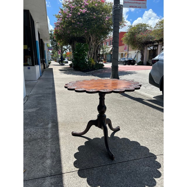 Impressive 19th Century English tilt top table handcrafted in mahogany with a scalloped edge and carved medallions on a...