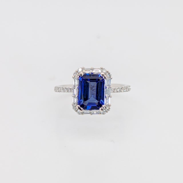 A tanzanite sits in a deep violet-blue at the centre of this solid 14K white gold ring, encircled by thirty-six earth-...