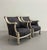 An elegant pair of Neoclassical-inspired bergère lounge chairs featuring a hand-distressed painted frame with carved...