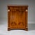 Biedermeier demi-cabinet in cherrywood with a concave front and flanking pilasters featuring gold-patinated capitals and...