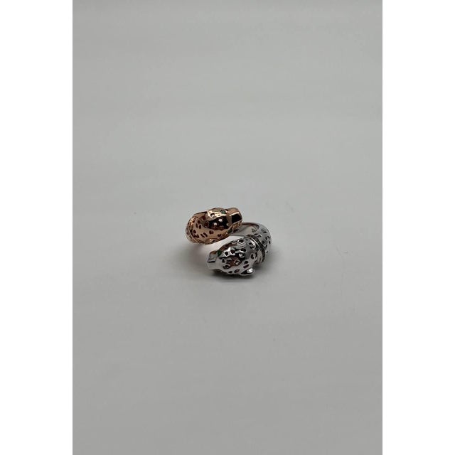 This captivating ring features a unique design with intertwined bands. The ring showcases a snow leopard & panther motifs,...
