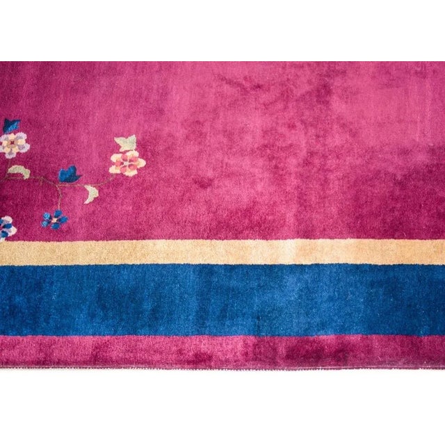 A wonderful early 20th century Chinese Art Deco rug with a cranberry field surrounded by a gold inner stripe, wide indigo...