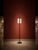 A modern minimalist floor lamp with a clean rectangular frame, square base, and cream fabric drum shade. The frame...