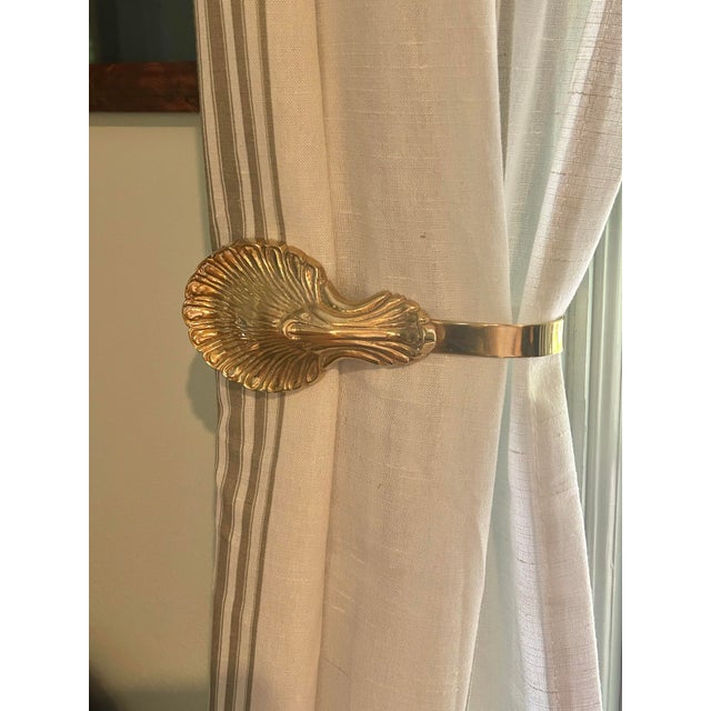This is a pair of vintage solid brass curtain tiebacks featuring a shell motif with acanthus-style detailing. The...