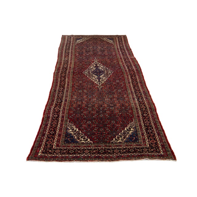 This Vintage Handmade Hamadan wool rug has a red field adorned with an allover floral design in multicolor accents. This...
