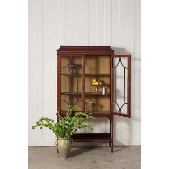 Edwardian mahogany glass-front display case featuring elegant spade legs, rich mahogany tones, and beautifully detailed...