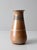 A vintage handmade studio pottery vase featuring a softly tapered form and a layered neutral glaze in warm peach and stone...