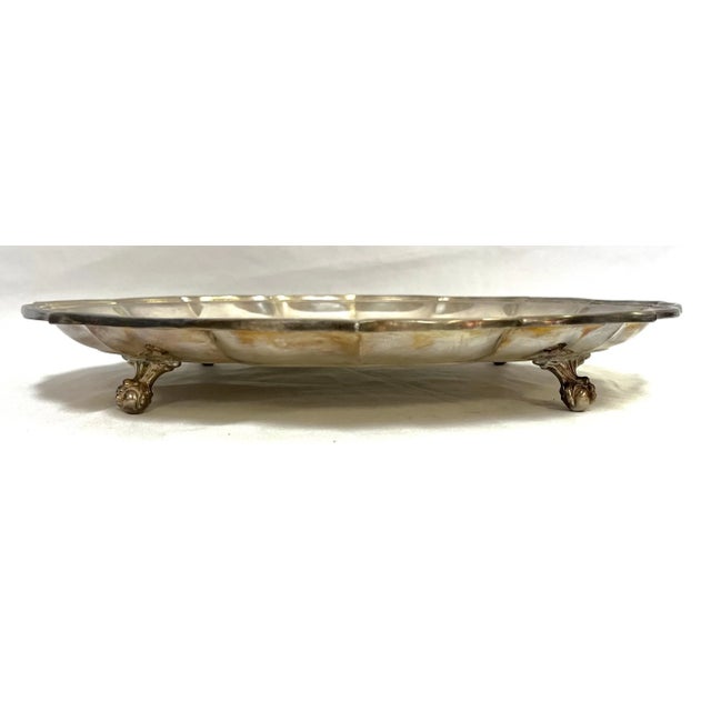 Lovely classic round silverplate tray! This vintage tray has pretty scalloped edges, and elegant ball and claw feet. The...