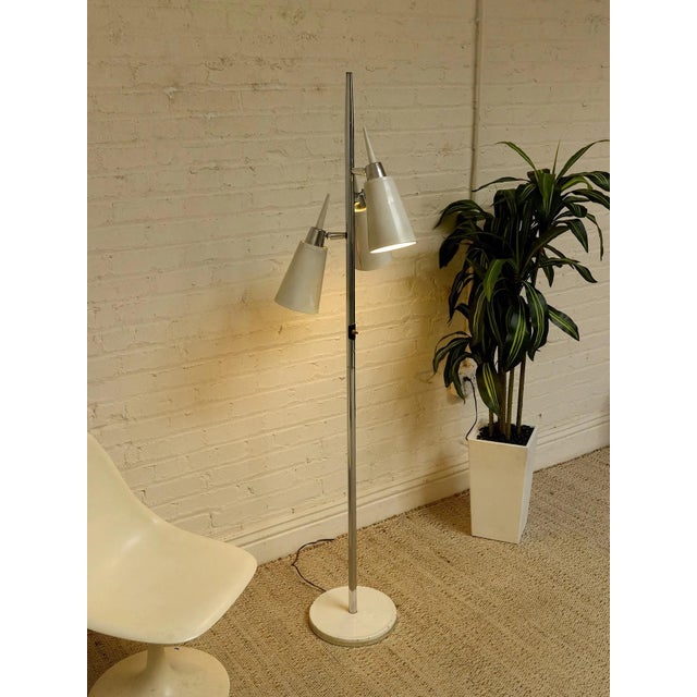 A sleek vintage Mid-Century Modern floor lamp featuring three adjustable cone shades mounted along a slender chrome pole....