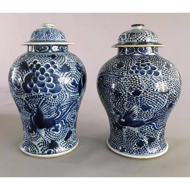 Chinese matched pair of porcelain blue and white vases and covers, decorated with flying phoenix birds on a background of...
