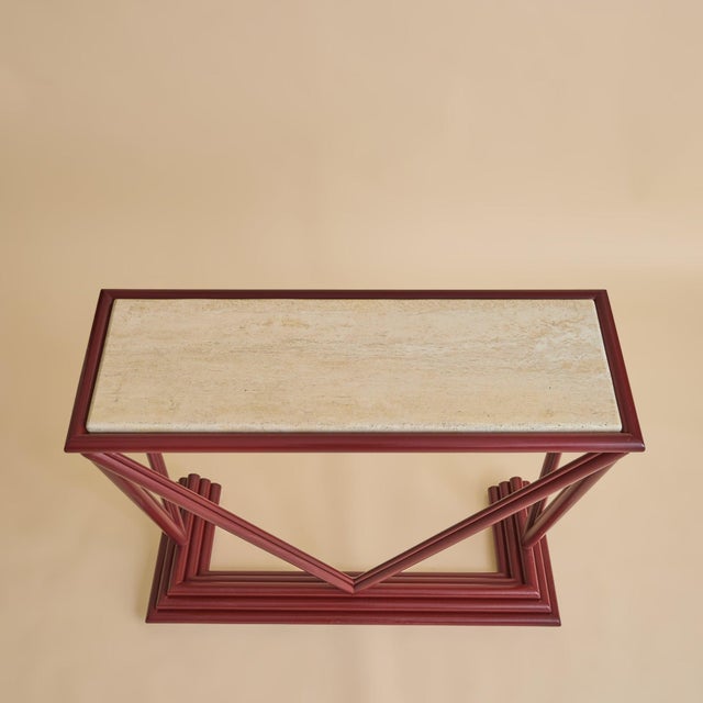 An Italian console from the late 1970s, defined by a sculptural wood frame finished in a saturated red lacquer. The...