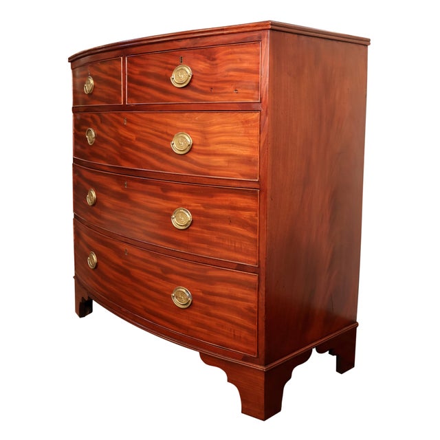 A Georgian Bowfront Chest of Drawers in Flamed Mahogany, English, circa 1820s, featuring two short drawers over three...