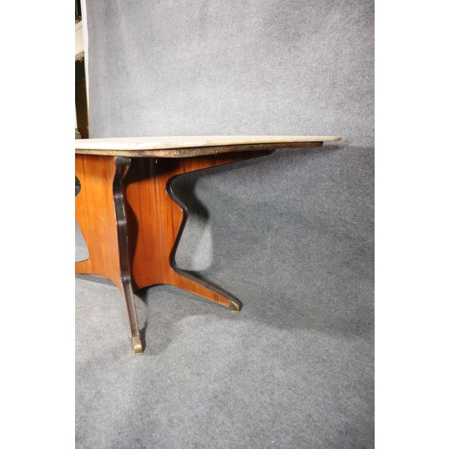 Mid-century Italian dining table with large marble top. Sculpted wood base with brass feet.