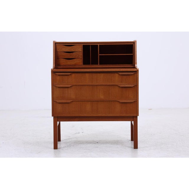 A beautiful teak secretary desk from the 1960s, featuring a clean Danish design and lovely grain. Its writing flap, small...