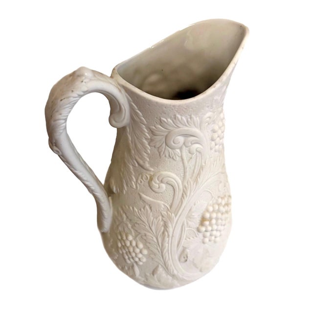 Beautiful 1980-91 vintage Parian ware pitcher featuring finely detailed raised grape, floral, and scrolling motifs. The...
