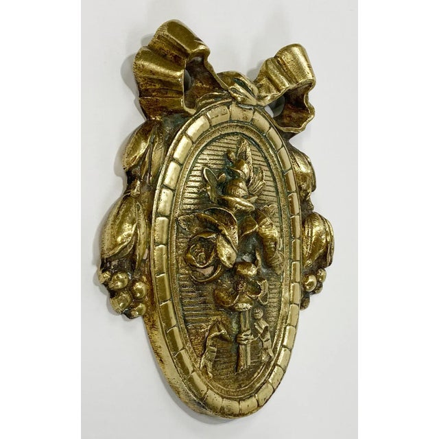 Vintage detailed brass door embellishment featuring ribbons to the top and flowers inside frame. A wonderful addition to...