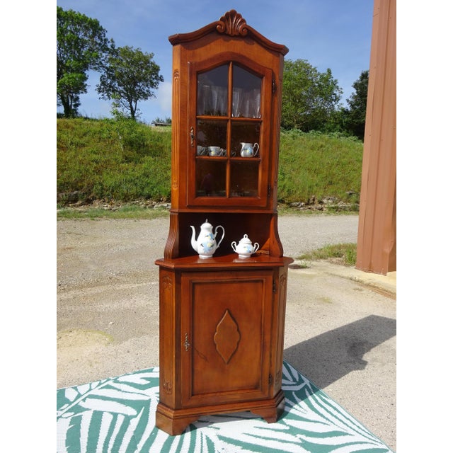 Small, tall, and narrow corner cabinet composed of two parts: a corner sideboard with one cupboard door topped by a...