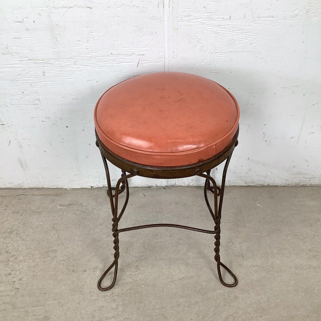 This vintage wrought iron stool offers a graceful balance of decorative detail and everyday function. The round...