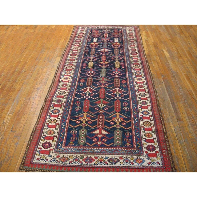 This blue tribal geometric antique wool-pile Northwest Persian hand-knotted hallway runner rug is a striking example of...