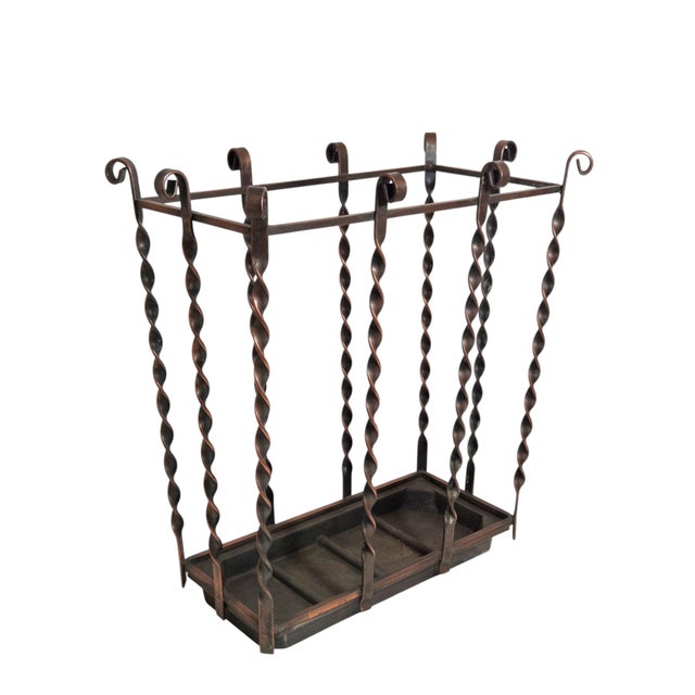 A vintage wrought iron sturdy umbrella stand crafted of copper colored heavy iron with decorative twisted spindle details...