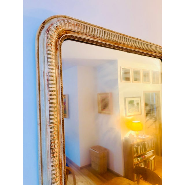 This large antique French Louis Philippe period overmantel mirror is rectangular with a slightly curved top, surrounded by...