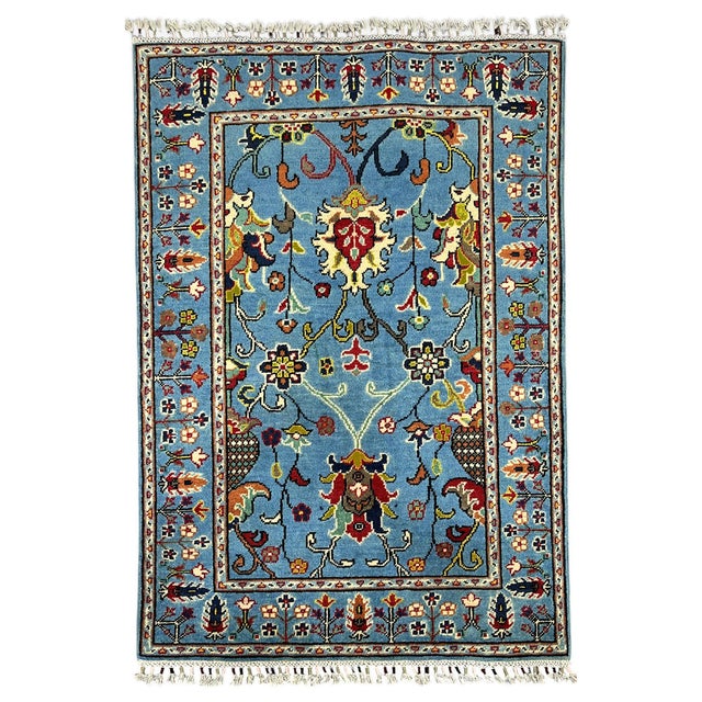 This naturally dyed wool rug features a blue field filled with scrolling vines and stylized flowers. Burgundy, cream,...
