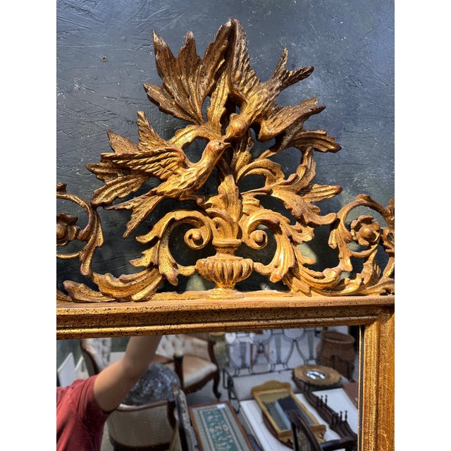 Mid Century Hollywood Regency style mirror featuring a beautiful carving of two birds covered in Gilt all over