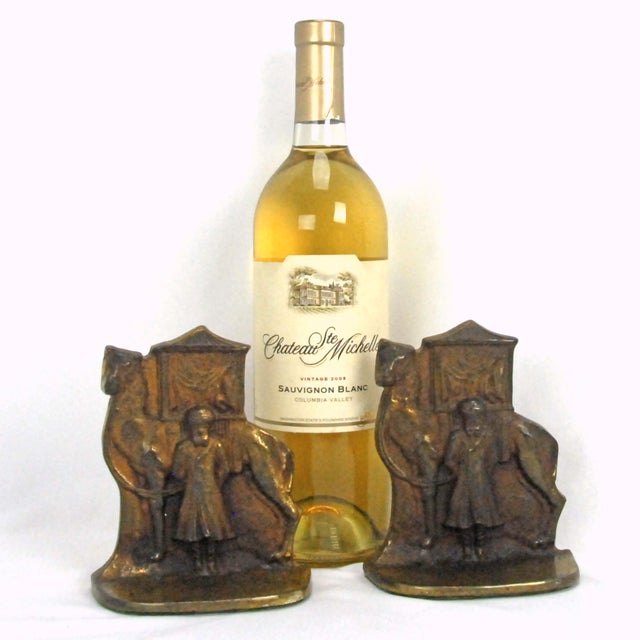 A striking antique pair of heavy cast iron bookends depicting a camel driver standing beside his camel and a covered...