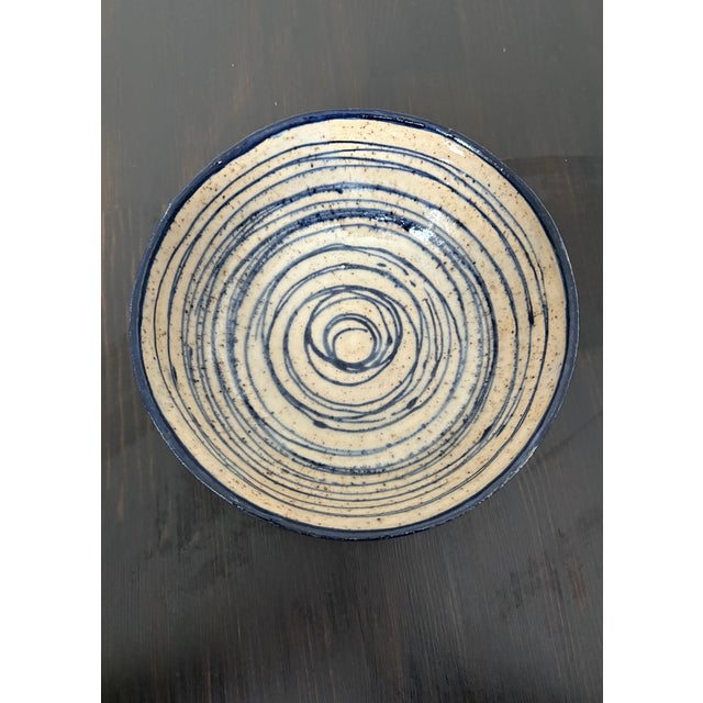 A substantial studio pottery bowl hand-thrown in speckled stoneware and decorated in cobalt blue and soft cream. A...