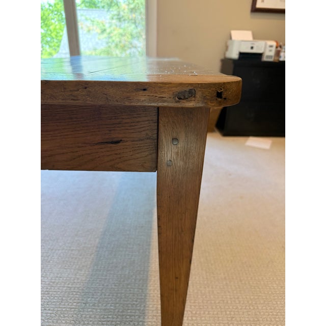 19th-century French provincial farmhouse table, featuring plank construction on the tabletop and breadboard ends. The warm...