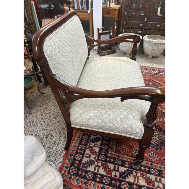 Lovely Edwardian small size mahogany loveseat having new neutral upholstery and brass casters. Gorgeous carving on arms...