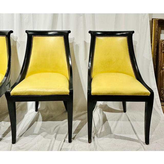 Set of four Empire-style gondola dining chairs with ebonized wood frames, curved backs, tapered saber legs, and antique...
