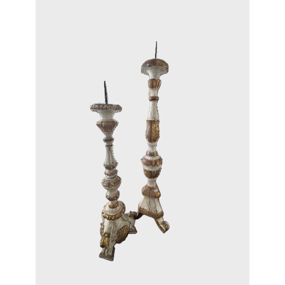 Sculptural asymmetrical pair of antique Italian carved wood candlesticks featuring a layered painted finish with parcel-...