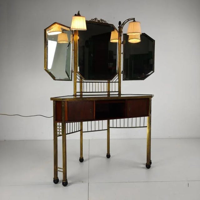 A beautiful antique French brass dressing table featuring multiple mirrors and two elegant lamps. This stunning piece...