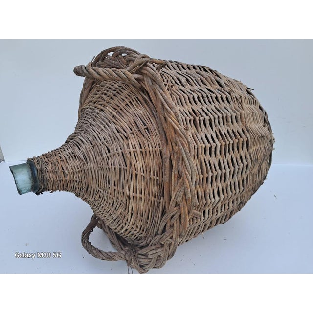 This large antique French demijohn (Damme Jeanne) bottle is housed in a woven wicker basket. It would have been used for...