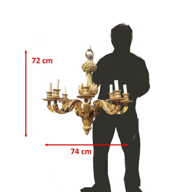 An imposing bronze chandelier, known as a "Mazarin" chandelier, with eight lights. It is decorated with faces on the...