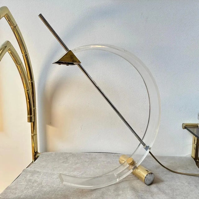 A design table lamp manufactured in Italy in the Eighties, the plexiglass arc is mounted on a brass metal base, and the...