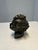 A finely crafted bronze bust depicting the head of a young child with detailed curls and a serene, upward gaze. This...