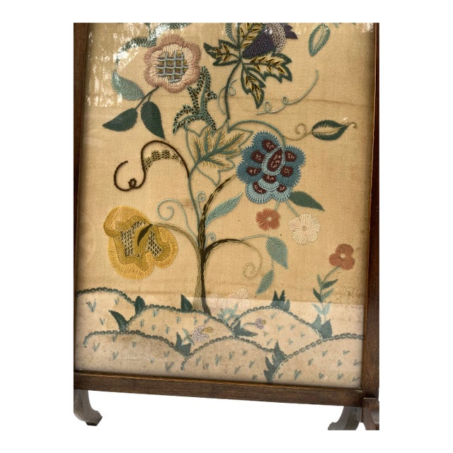 A single antique wood standing fireplace screen with framed crewel work textile featuring multicolor stylized flowers and...