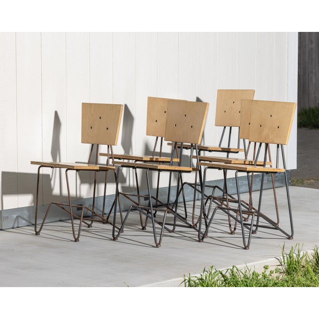 Set of six industrial dining chairs constructed from molded plywood and bent steel, reflecting the utilitarian design...