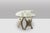 A Brutalist-style coffee table featuring a sculptural, organic base made of reconstituted stone and a glass top. from the...