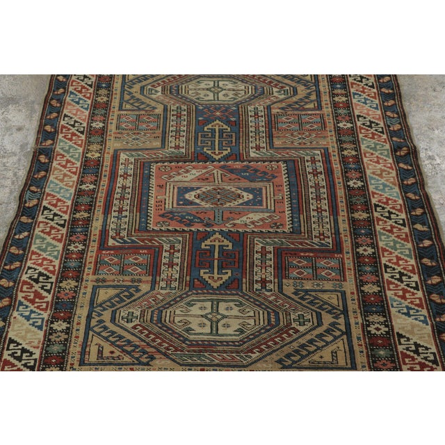 Hand-knotted in wool, this 4x5 Antique Caucasian rug, circa 1890–1899, features stacked geometric medallions, shield...